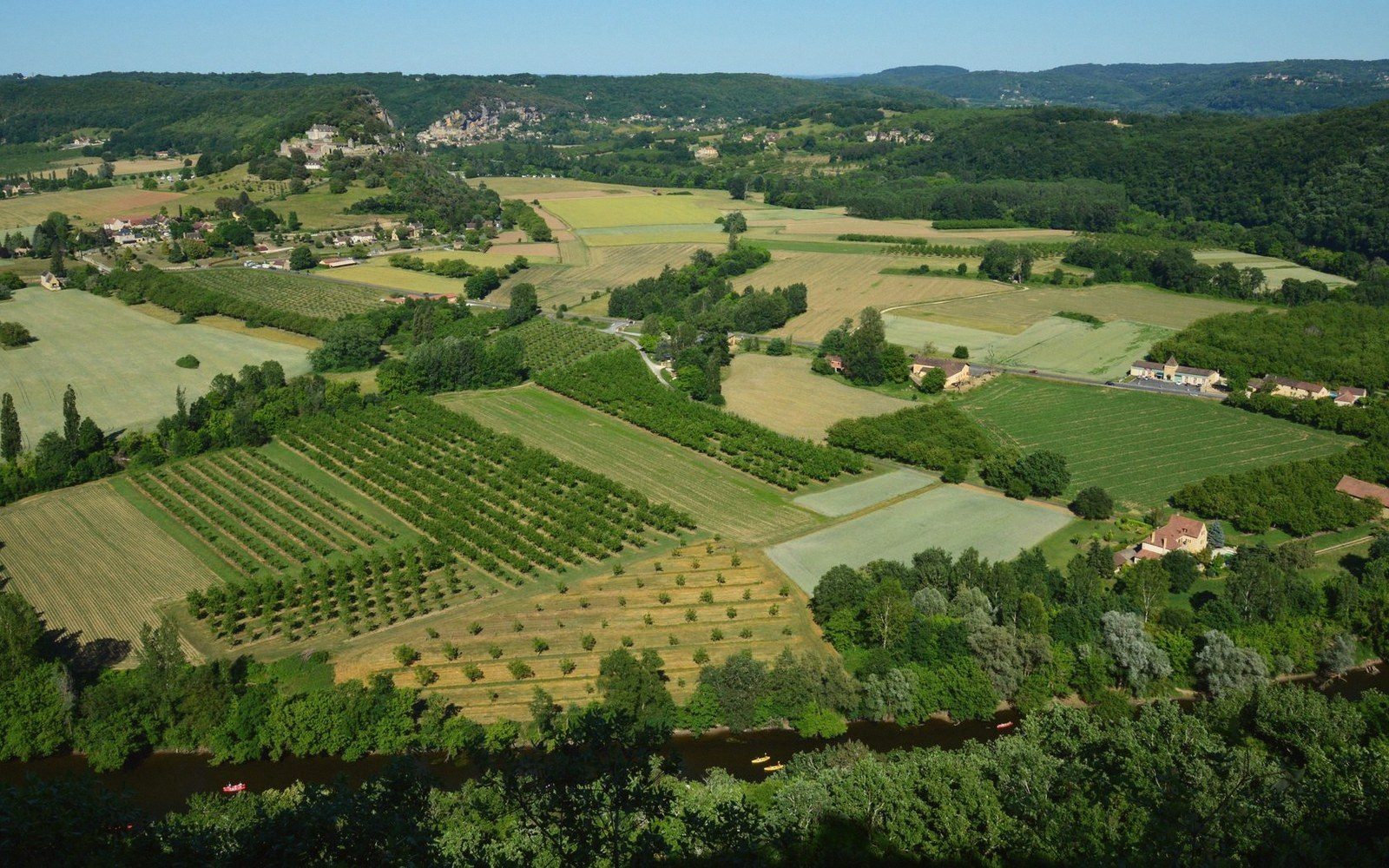 The Calavon valley corridor from above, the N100 threading through orchards and farmland, the massif rising on the left