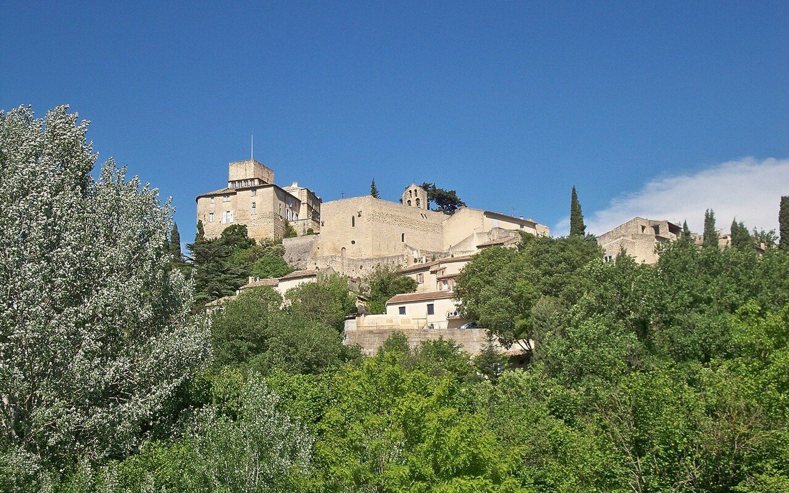Hilltop village of stone buildings and a church tower rising above green trees