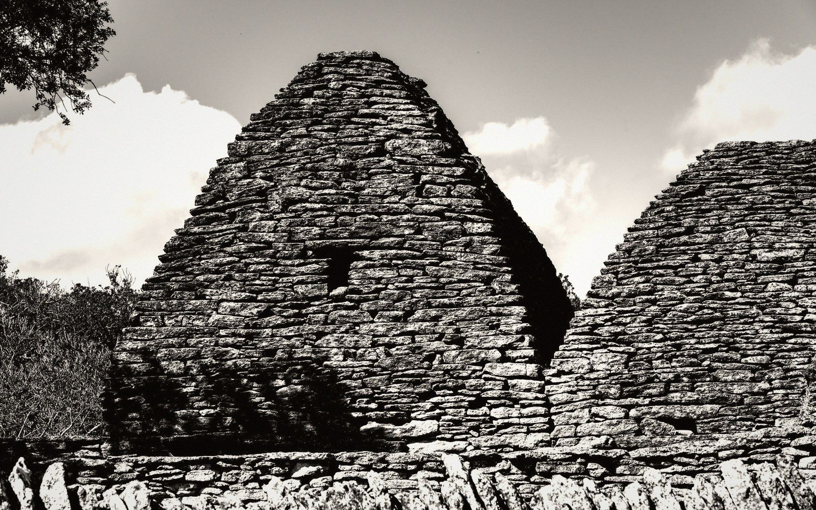 Conical dry-stone borie huts with corbelled roofs stand beside a low stone wall