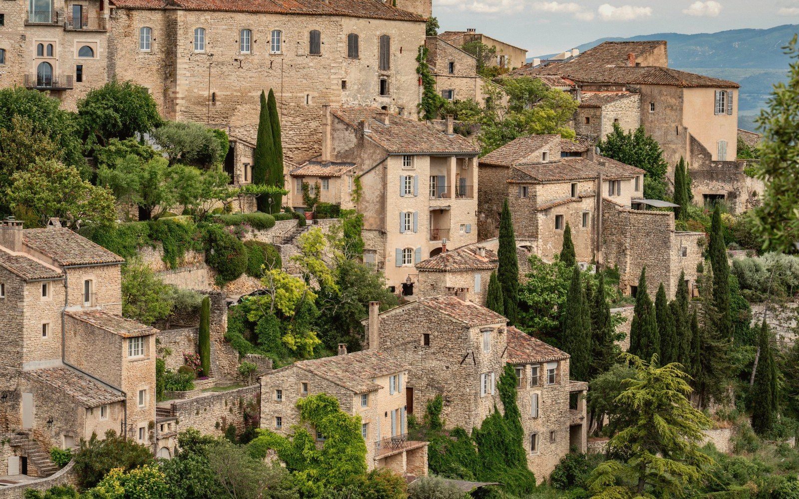 Stone houses with tiled roofs cascade down a hillside in the village of Gordes