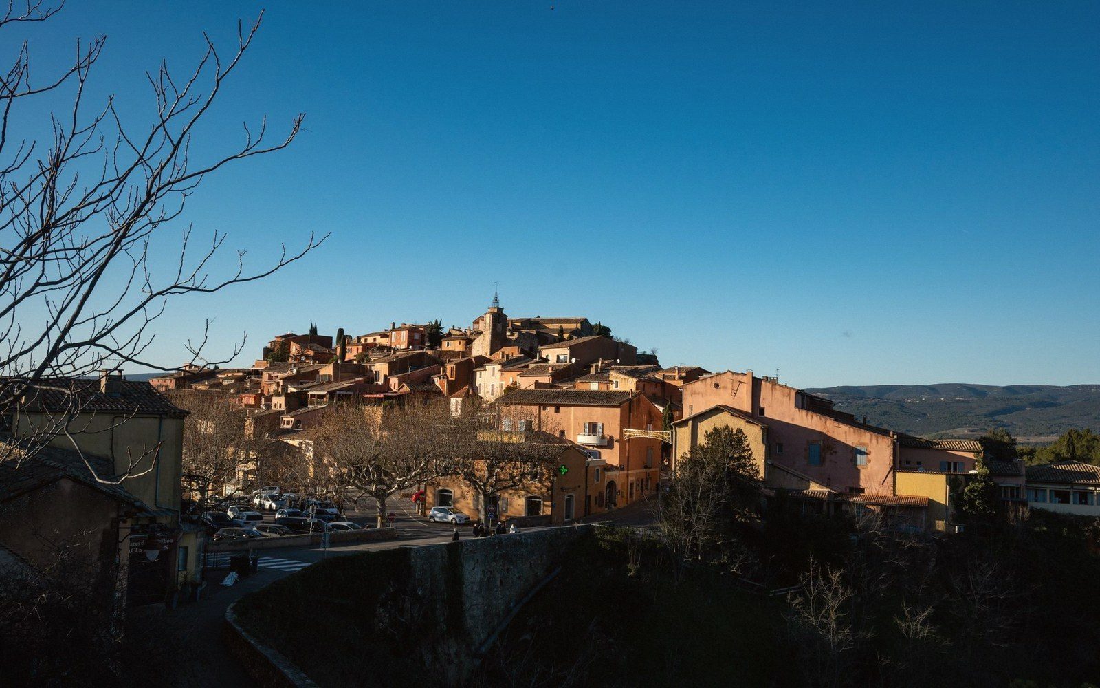 Ochre-colored hillside village overlooking a valley under a clear blue winter sky