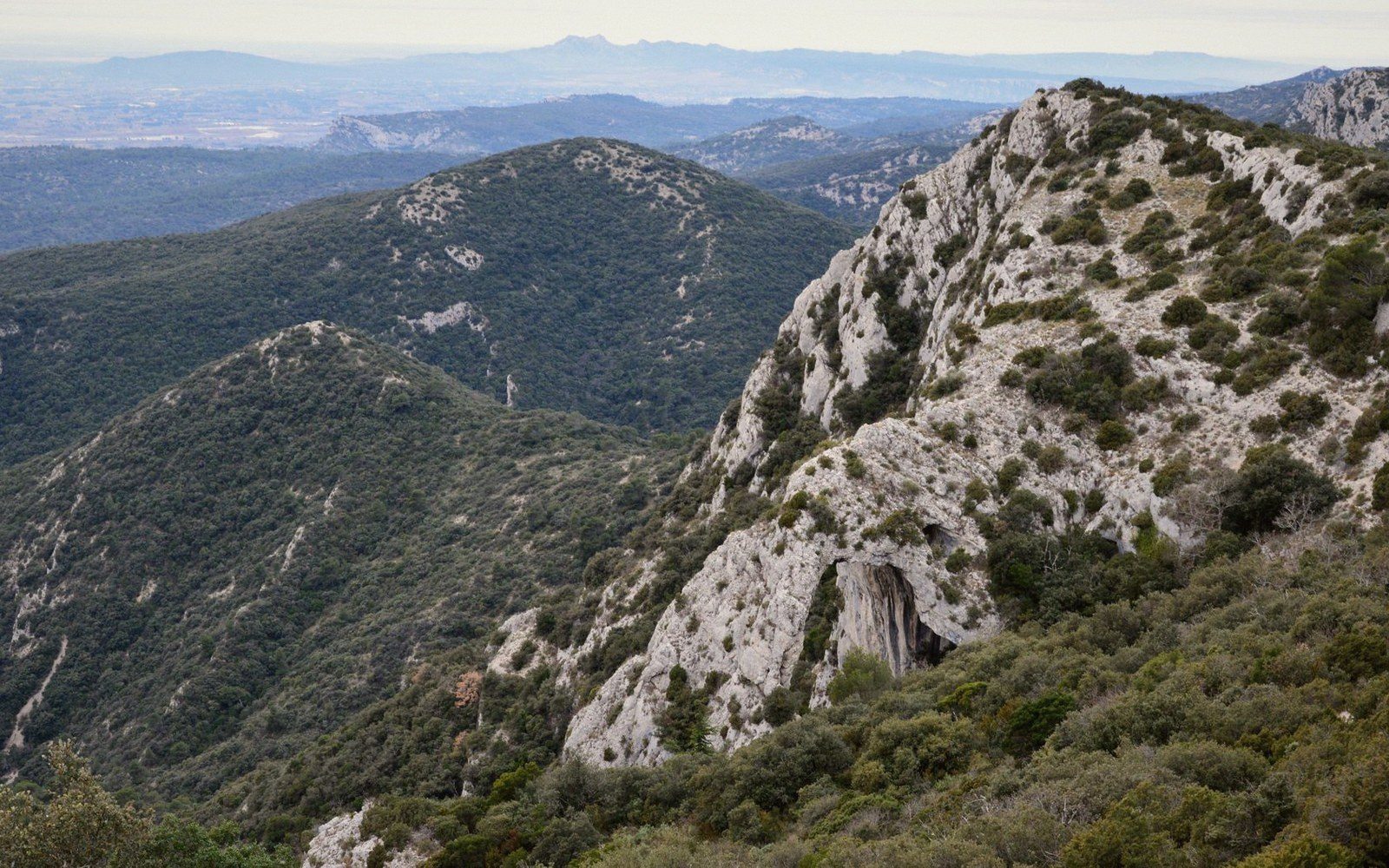 Rocky ridgeline of the Petit Luberon with scrub-covered slopes and distant hazy hills