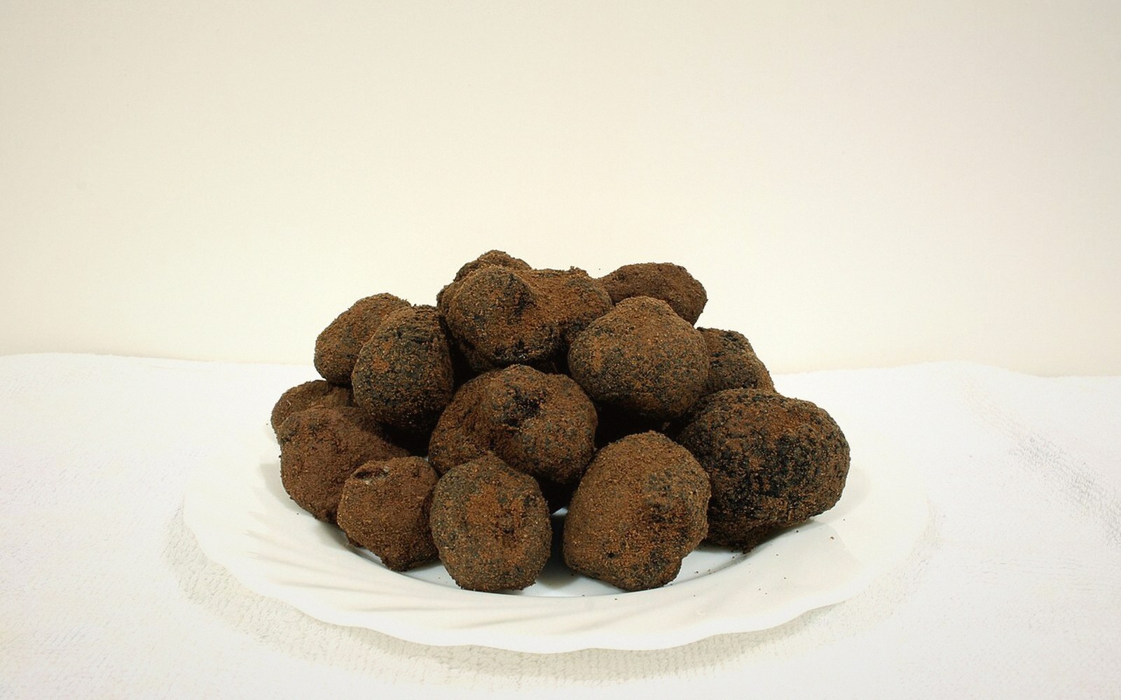 A pile of black truffles stacked on a white plate